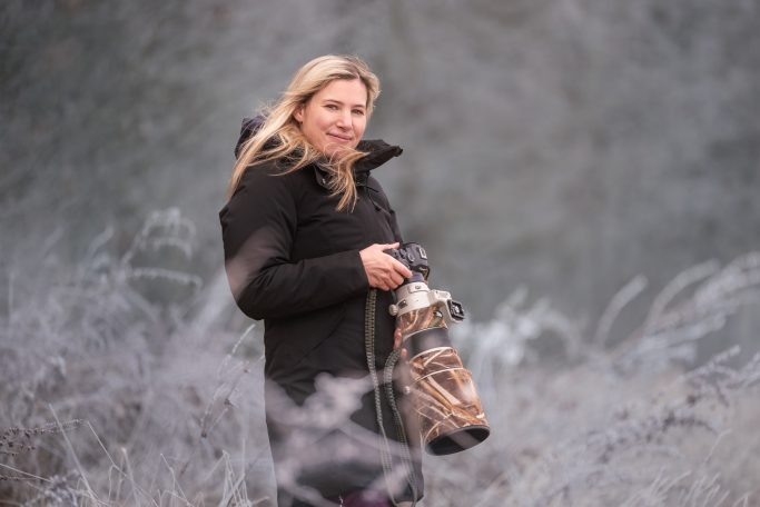 Frau mit Kamera in einem frostigen Landschaftssetting.